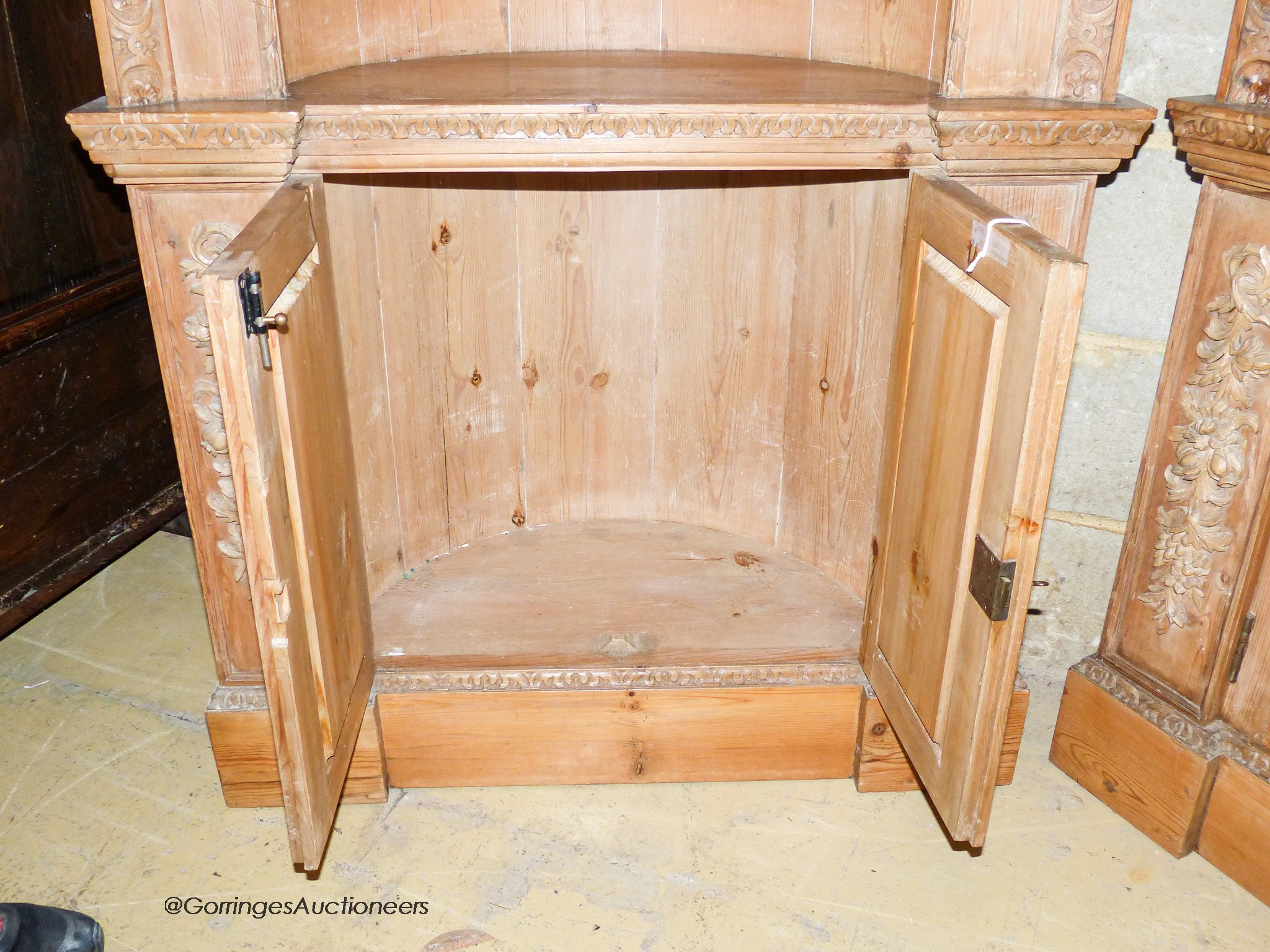 A pair of George III style carved stripped pine niche barrel back open corner cupboards, width 90cm, depth 40cm, height 208cm